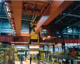 A coil crane transports rolls of sheeting within the works.